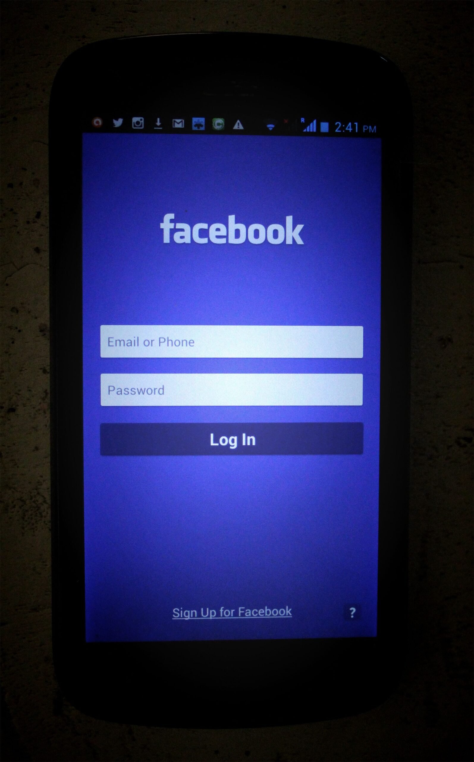 Dark smartphone screen showing Facebook login page with input fields.